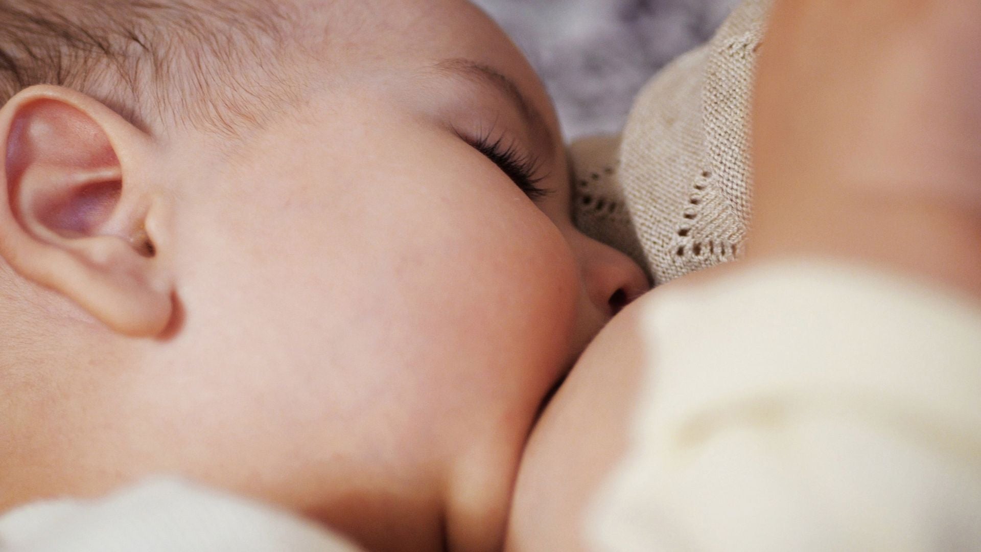 Parent feeding newborn baby, close up of baby’s face during feed