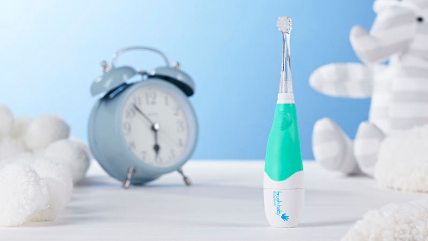 A brush-baby kids toothbrush with a pale blue background and a pale blue clock