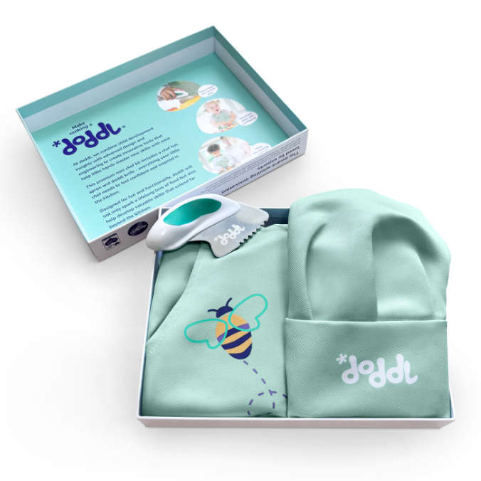Lioght aqua toddler apron with bee design and matching hat and doddl knife, displayed with a box on a white background.
