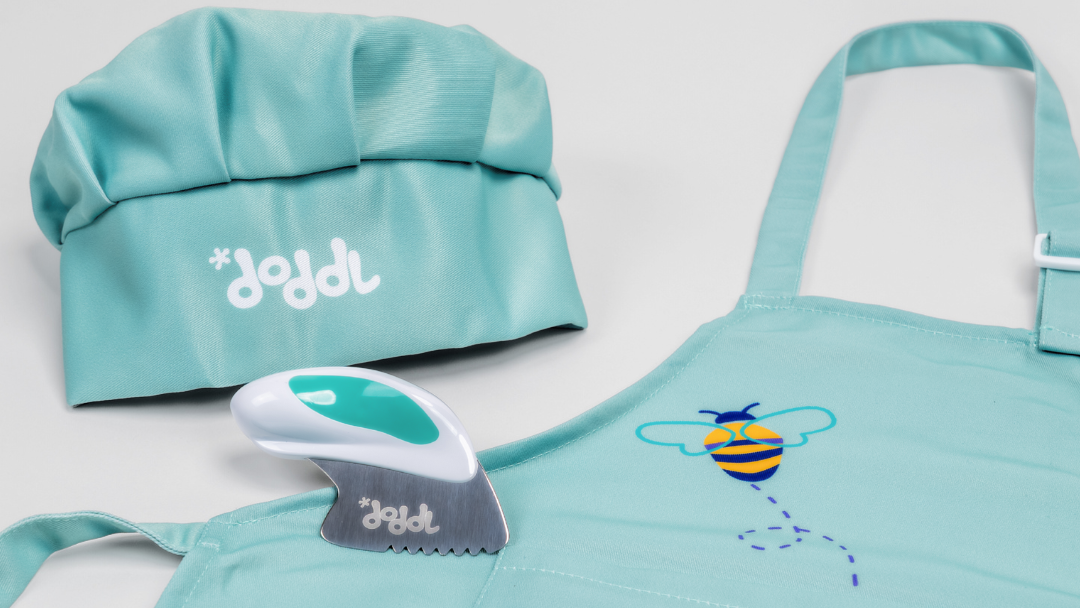 Teal children's apron, hat, and doddl with bee design on a light gray background