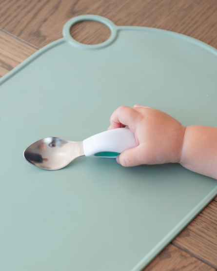 A baby holding a doddl spoon in a relaxed grip