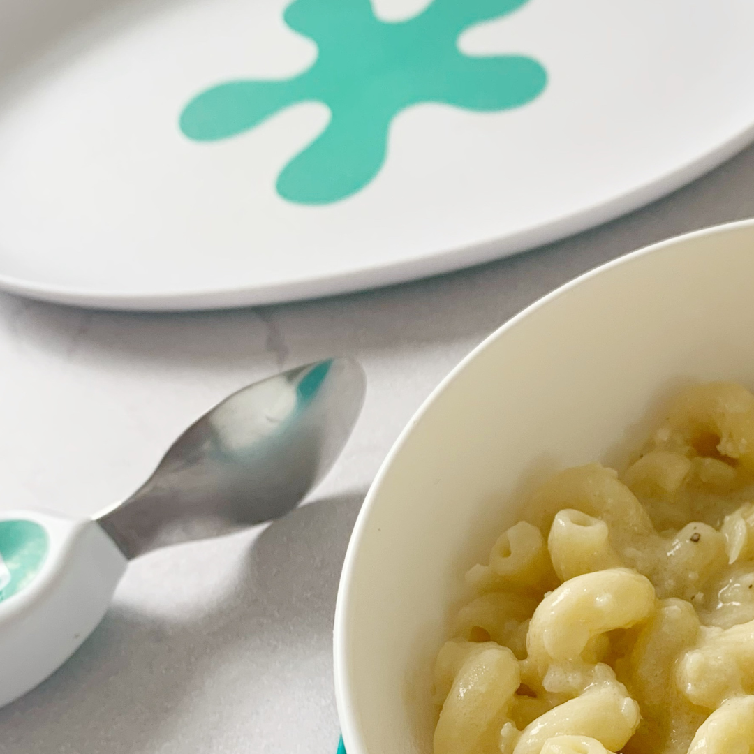 Cheesy cauliflower pasta with a white and aqua doddl plate and spoon