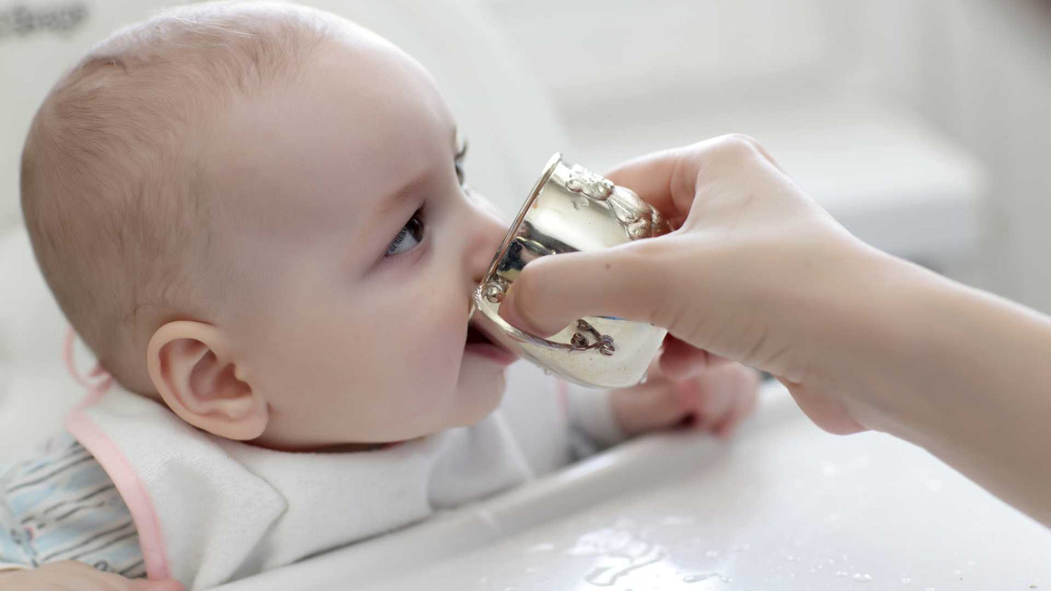 Baby sipping water from an open cup