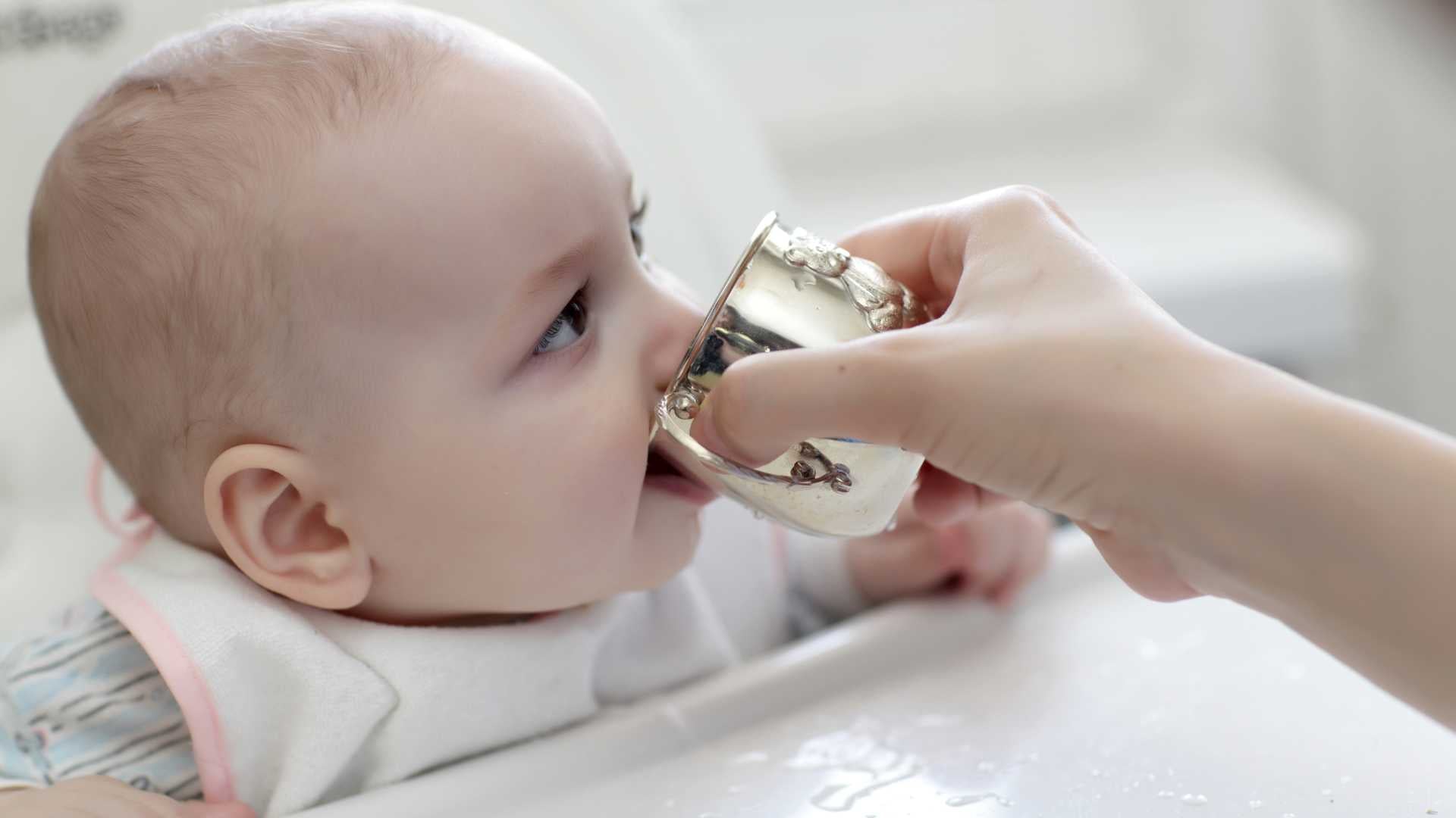 Baby sipping water from an open cup