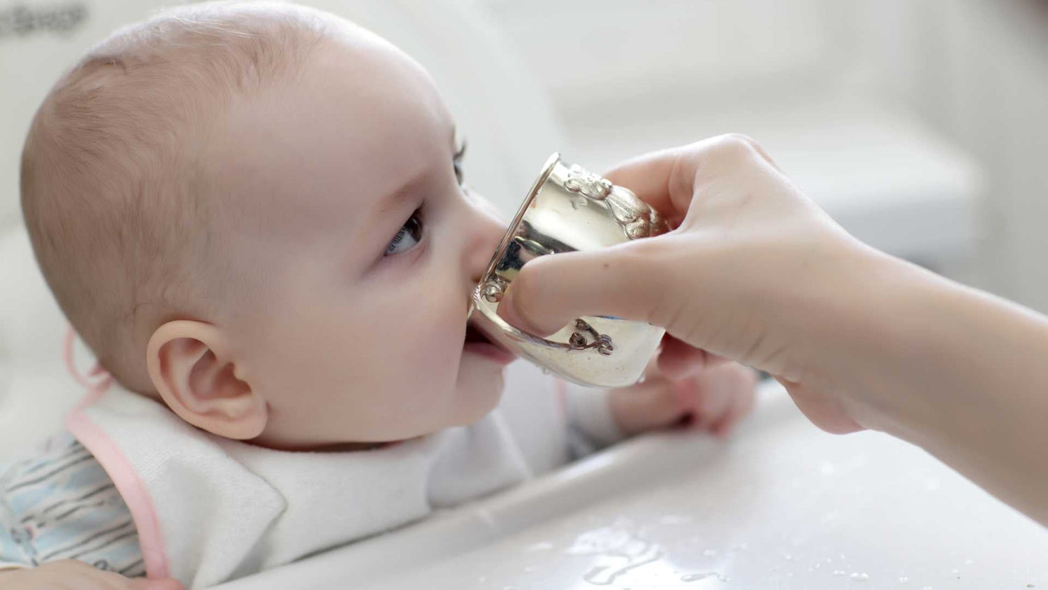 Baby sipping water from an open cup