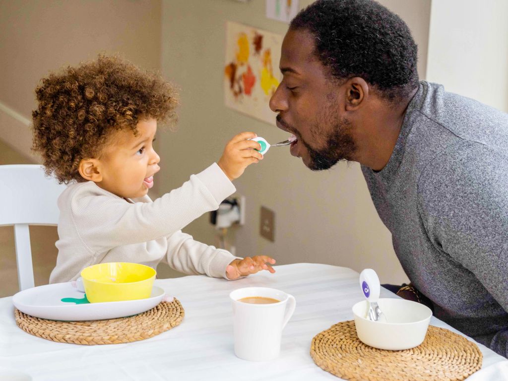 Importance of family meal times - little boy and his dad sit at the table eating with doddl cutlery