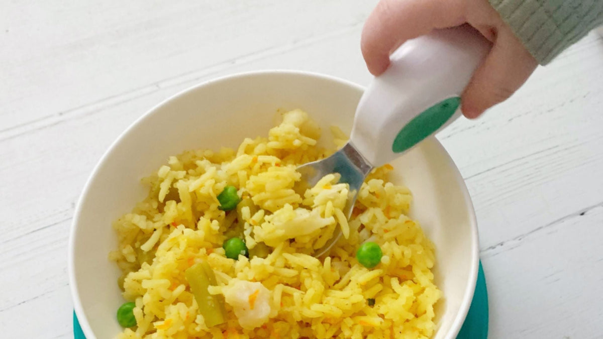 toddler hand holding a doddl toddler spoon dipping into a biryani