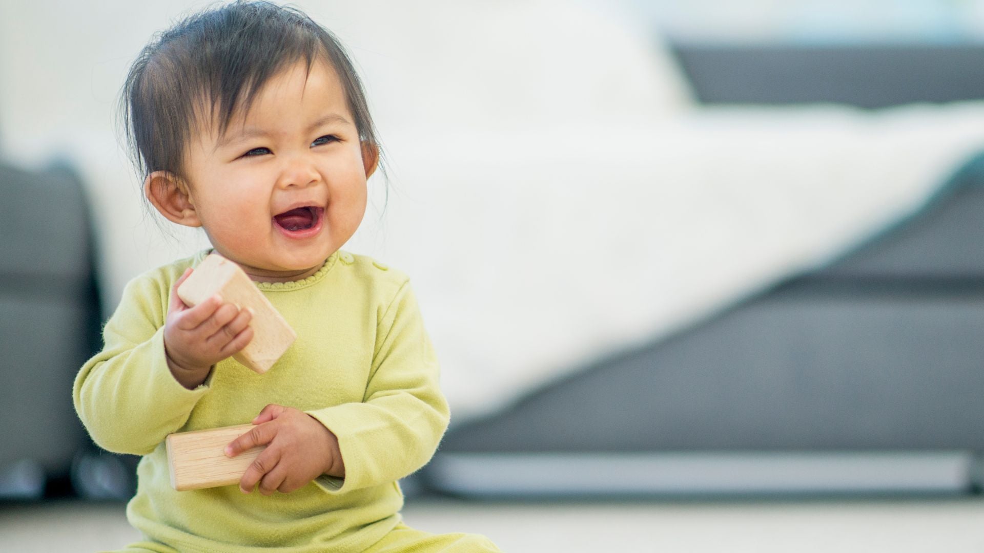 toddler child smiling happily while holding building blocks