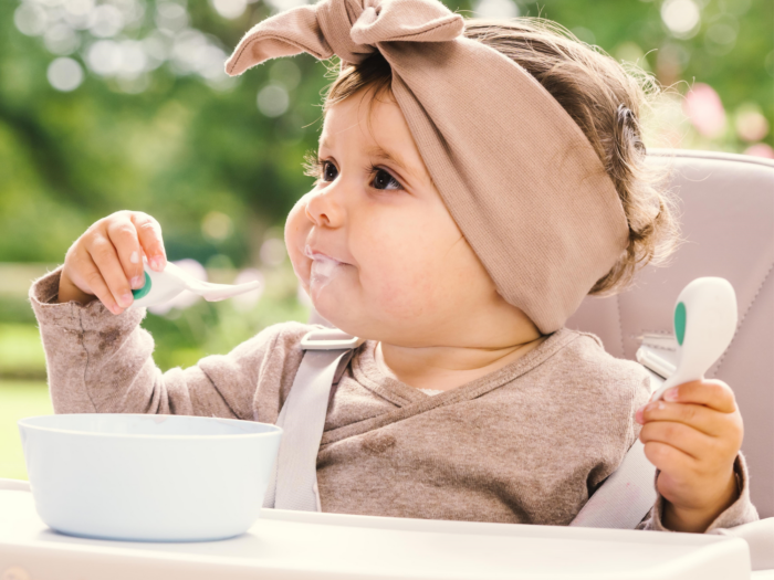 How to teach a toddler to feed themselves - little girl using a doddl baby spoon|Stacey Zimmels - FeedEatSpeak bio photo