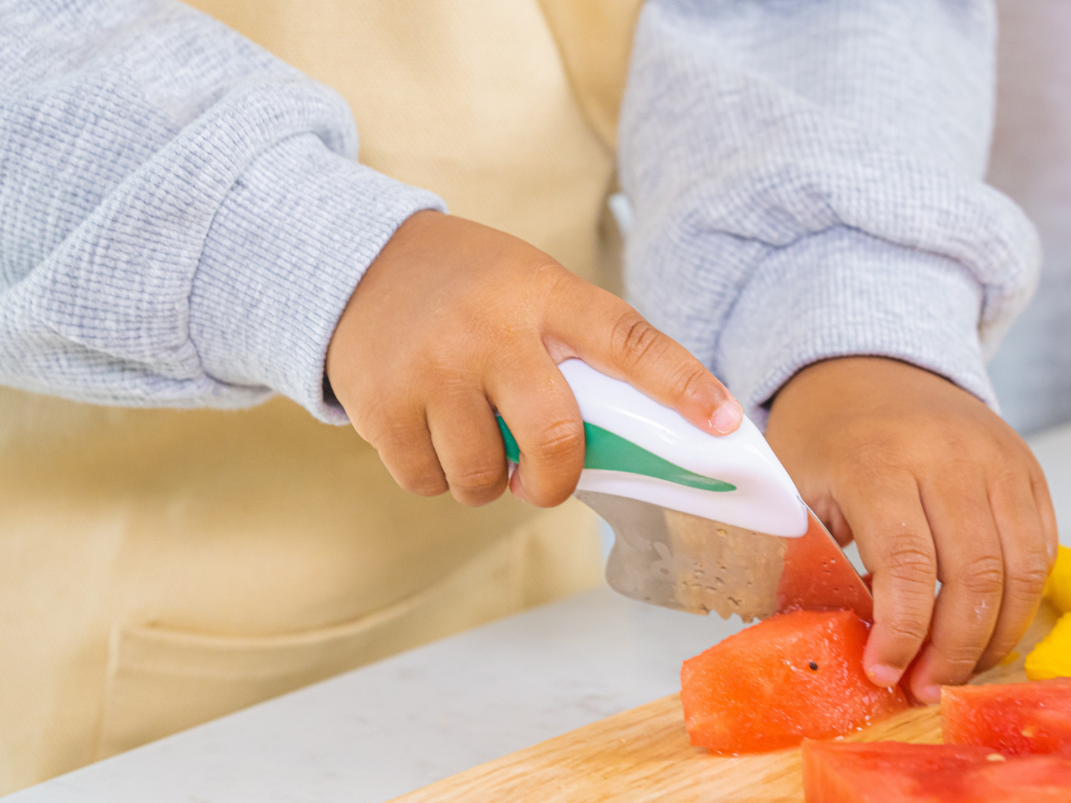 introducing the doddl toddler knife. little hands holding the doddl knife safely chopping a carrot into slices