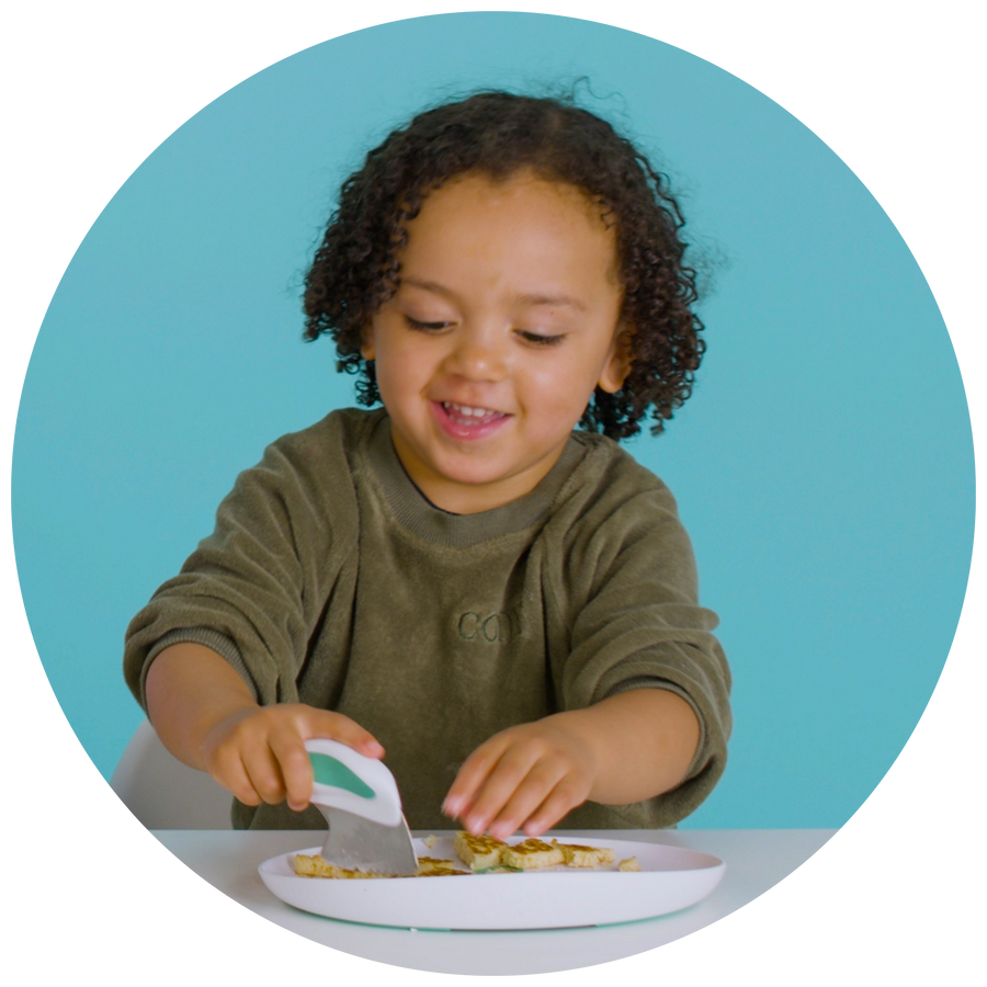Toddler eating with a doddl knife and fork