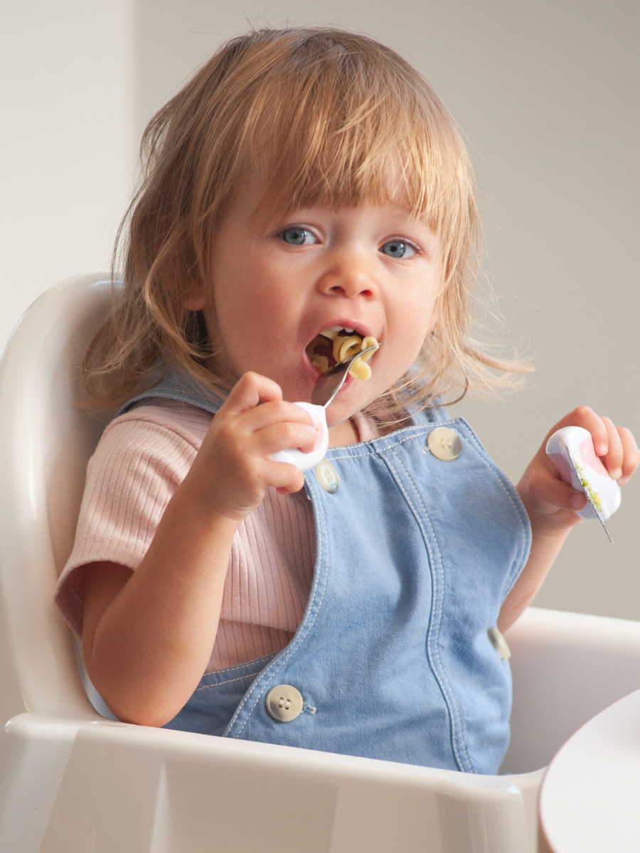 A toddler eating confidently with a doddl fork