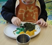 A child at a COGEHAM nursery eating vegetables from a doddl plate