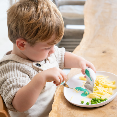 Child eating at a table with a doddl plate of food